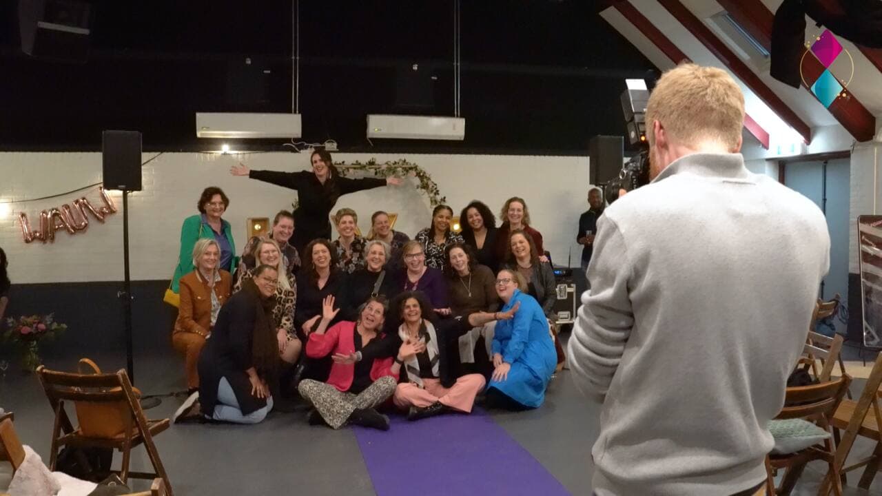 Grote groepsfoto tijdens een boeklancering, vastgelegd door de camera