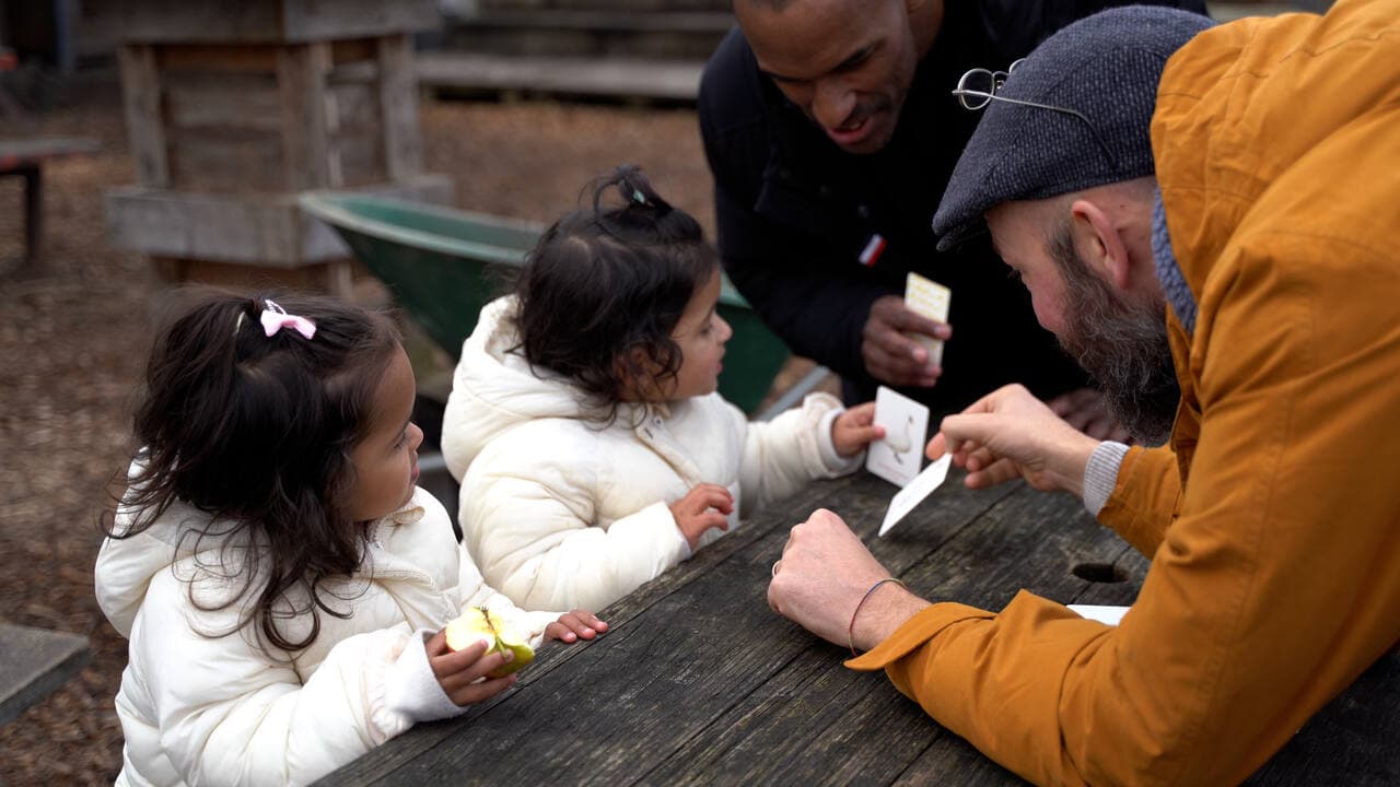 Begeleiders spelen een kaartspel met kinderen tijdens een open dag