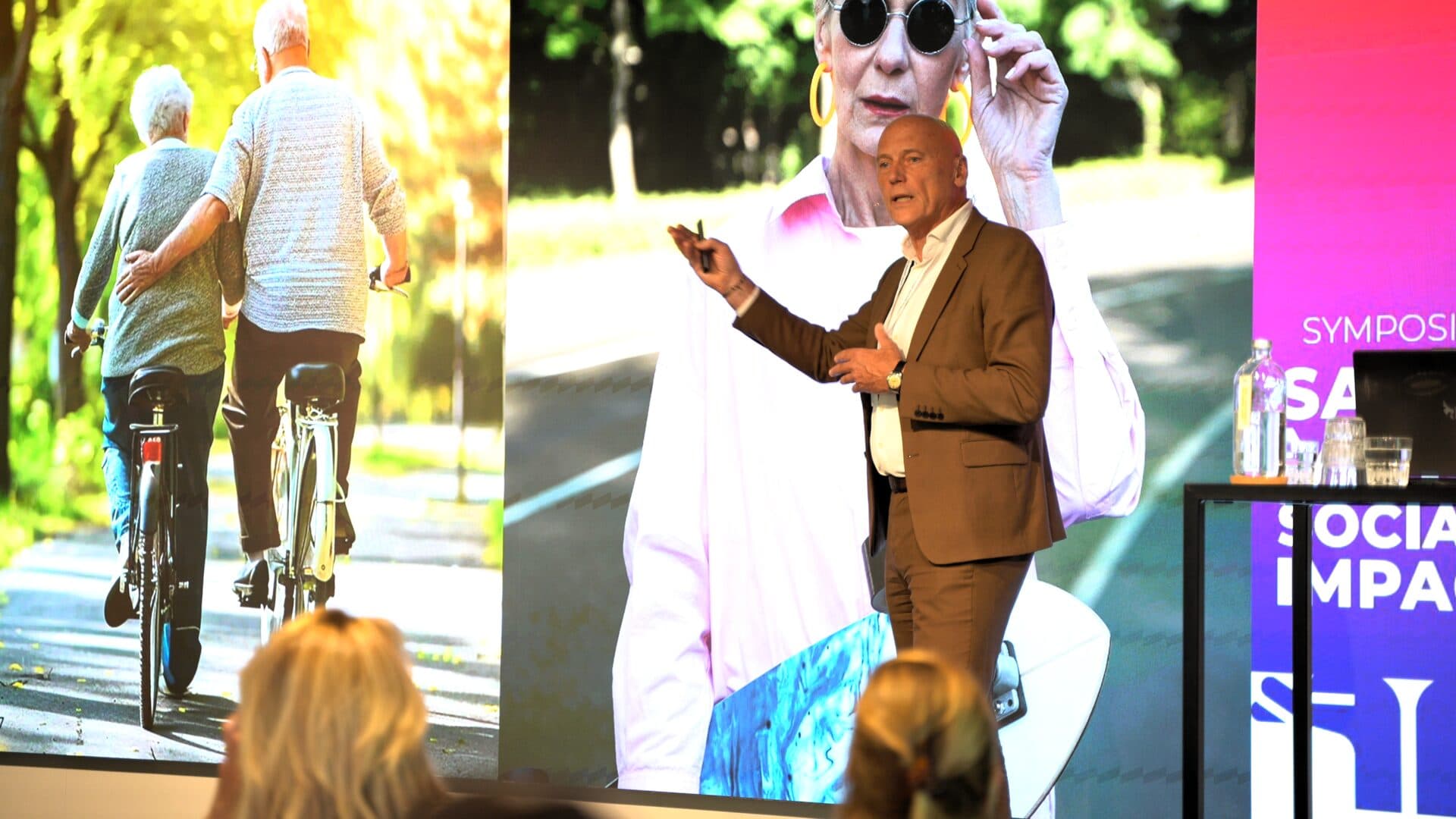 Spreker met presentatie op groot scherm tijdens een symposium