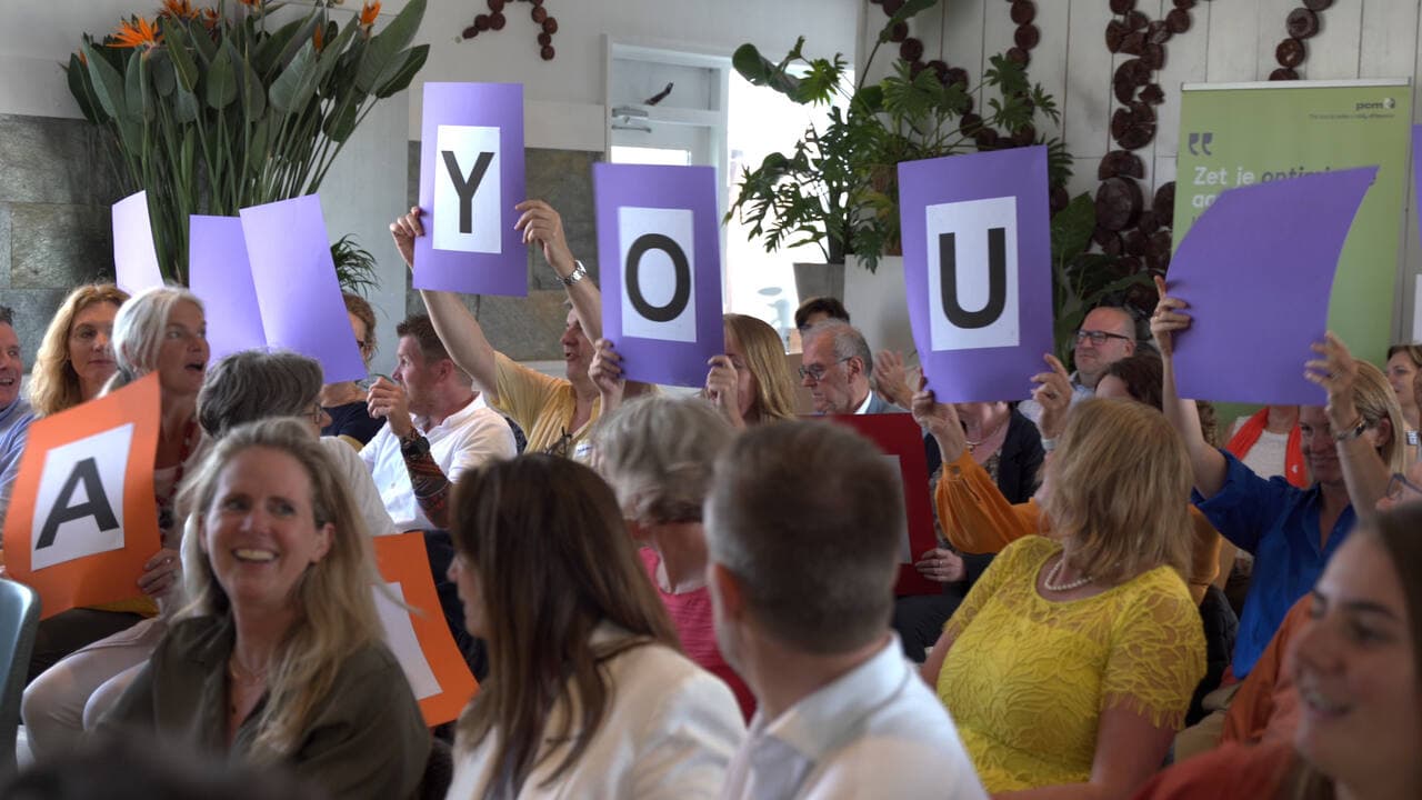 Deelnemers houden letterkaarten omhoog tijdens een interactieve sessie