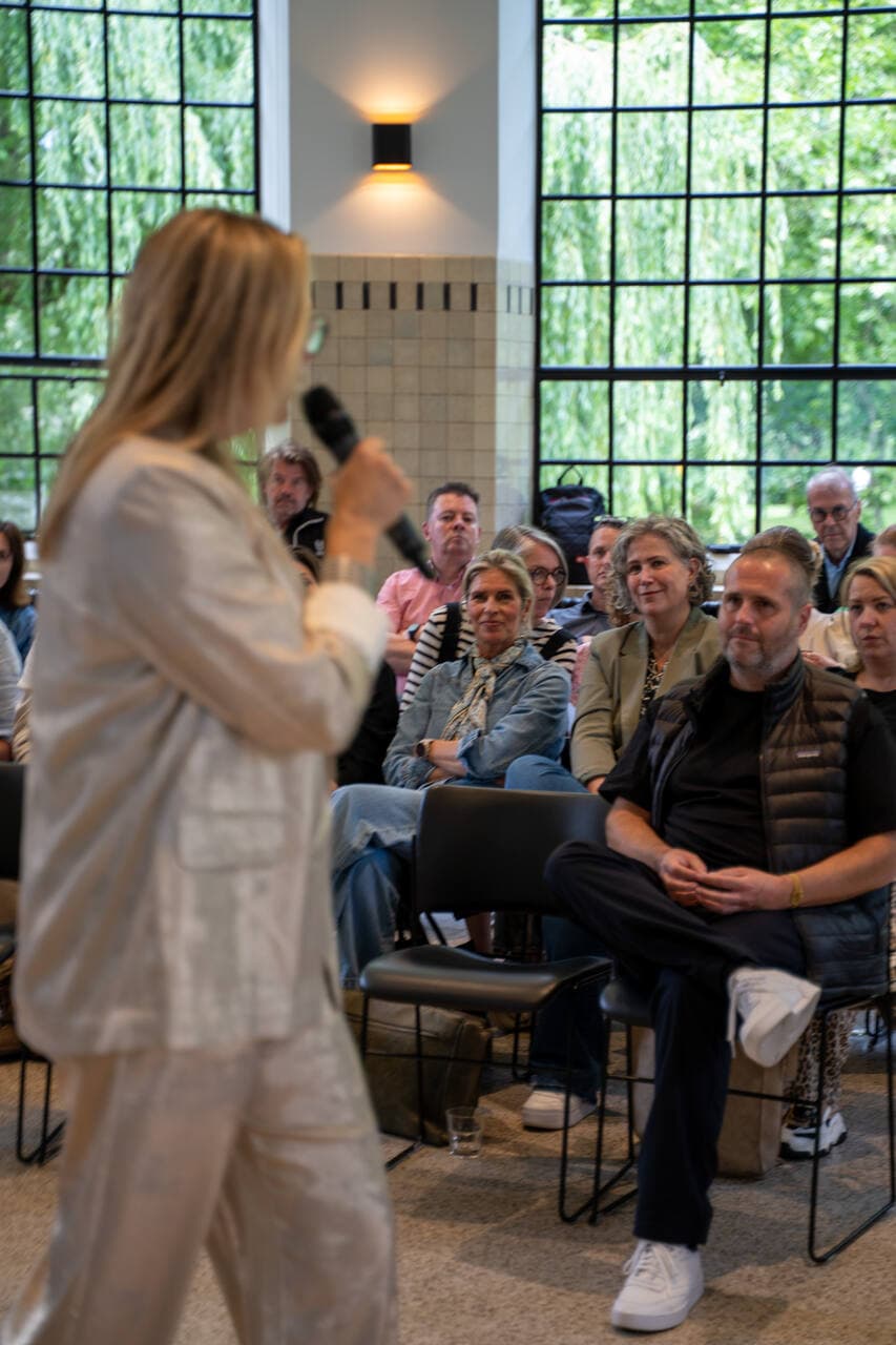 Spreker met microfoon voor een groep deelnemers